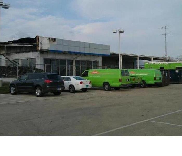 Car dealership that had suffered a fire that has SERVPRO vehicles out in front of it 