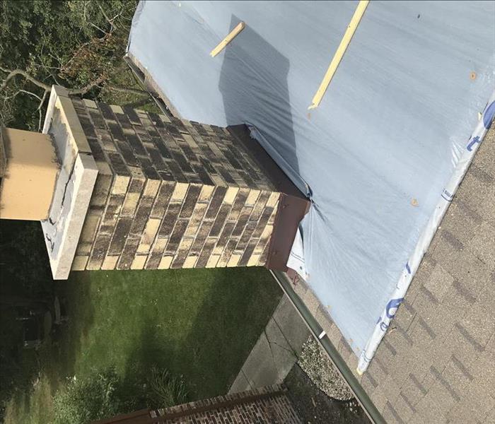 a chimney that has had a tarp put around it after a storm event put a hole in the roof