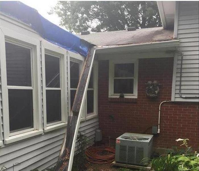 The side of a house with the gutter falling off the roof