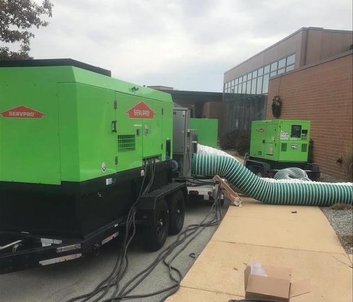 Large green generators in front of a school
